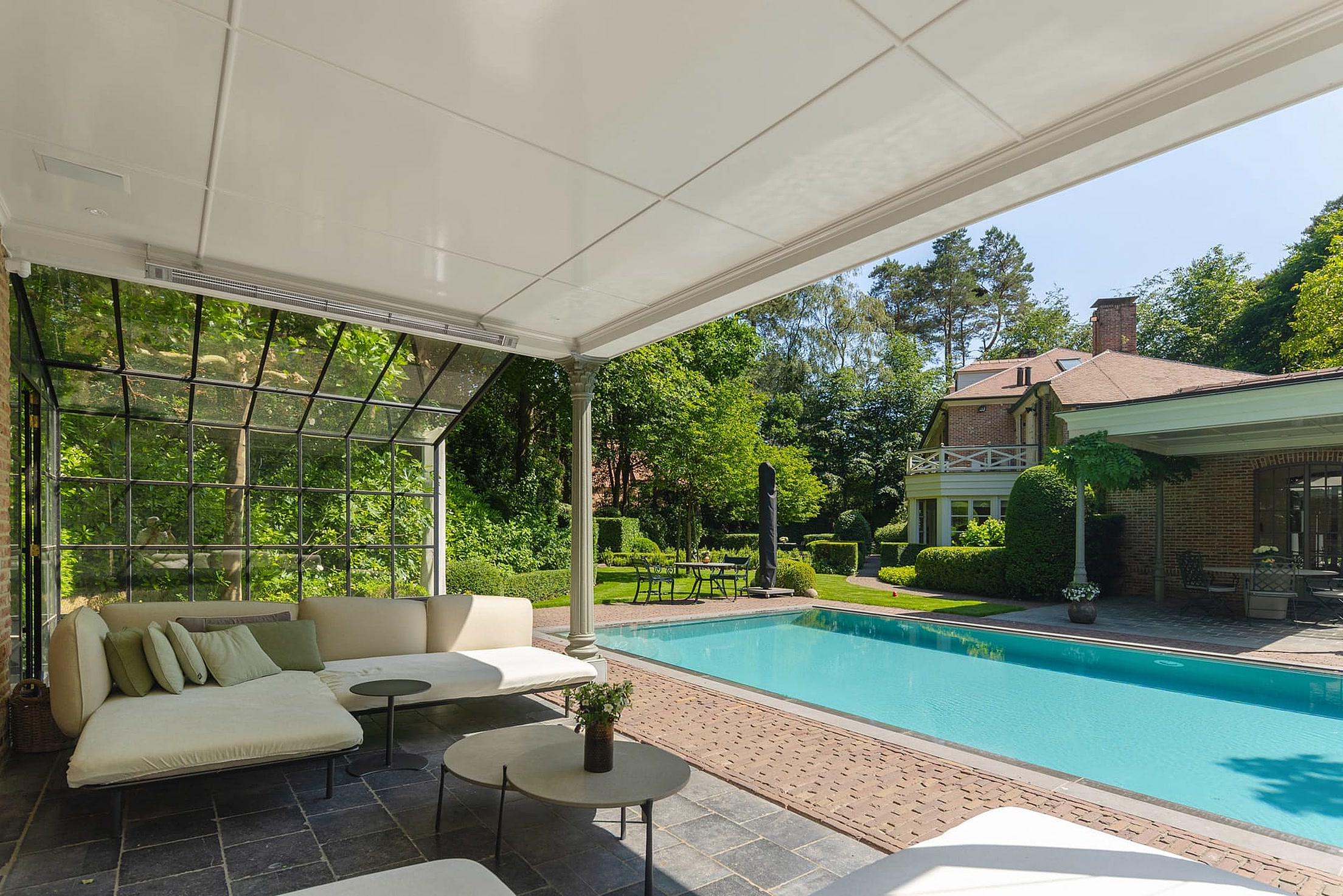 Zwembad met overdekte lounge en poolhouse in een aangelegde tuin