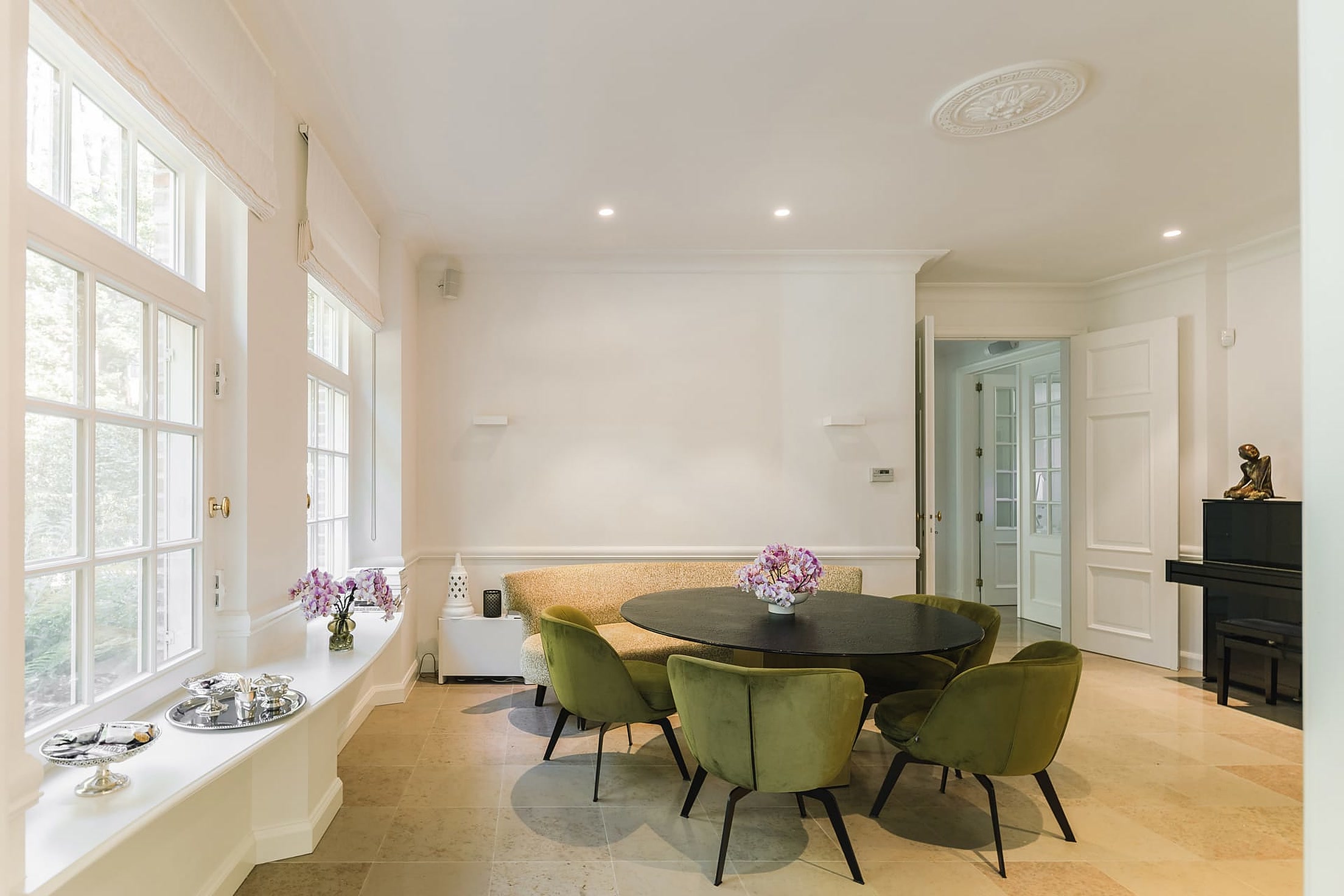 Eetkamer met ronde tafel en brede ramen op het groen