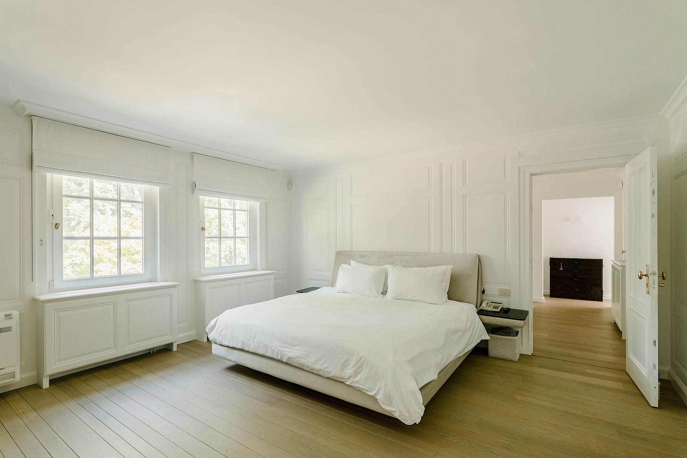Rustige witte slaapkamer op parket met groot raam